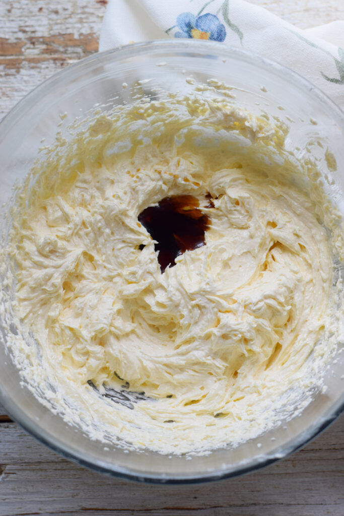 Adding vanilla extract to batter in a glass bowl.