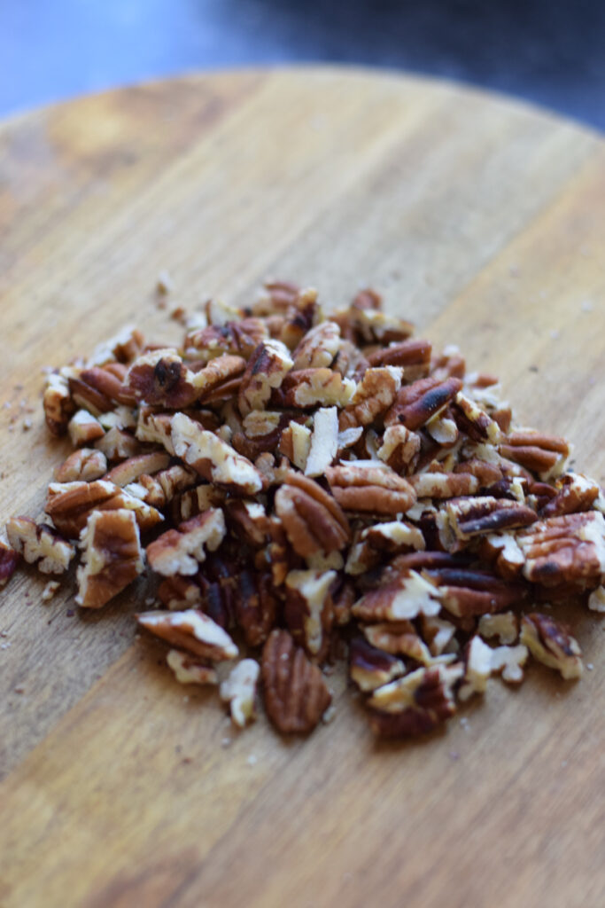 Roughly chopped pecans on a wooden board.