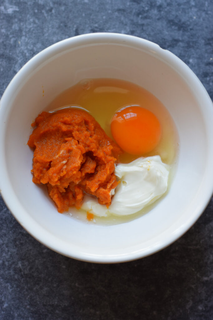 Adding pumpkin puree, egg and cream in a bowl.