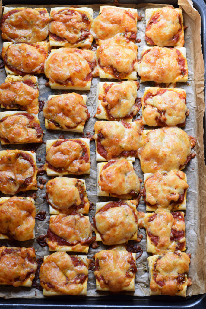 Puff pastry pizza bites on a baking tray.