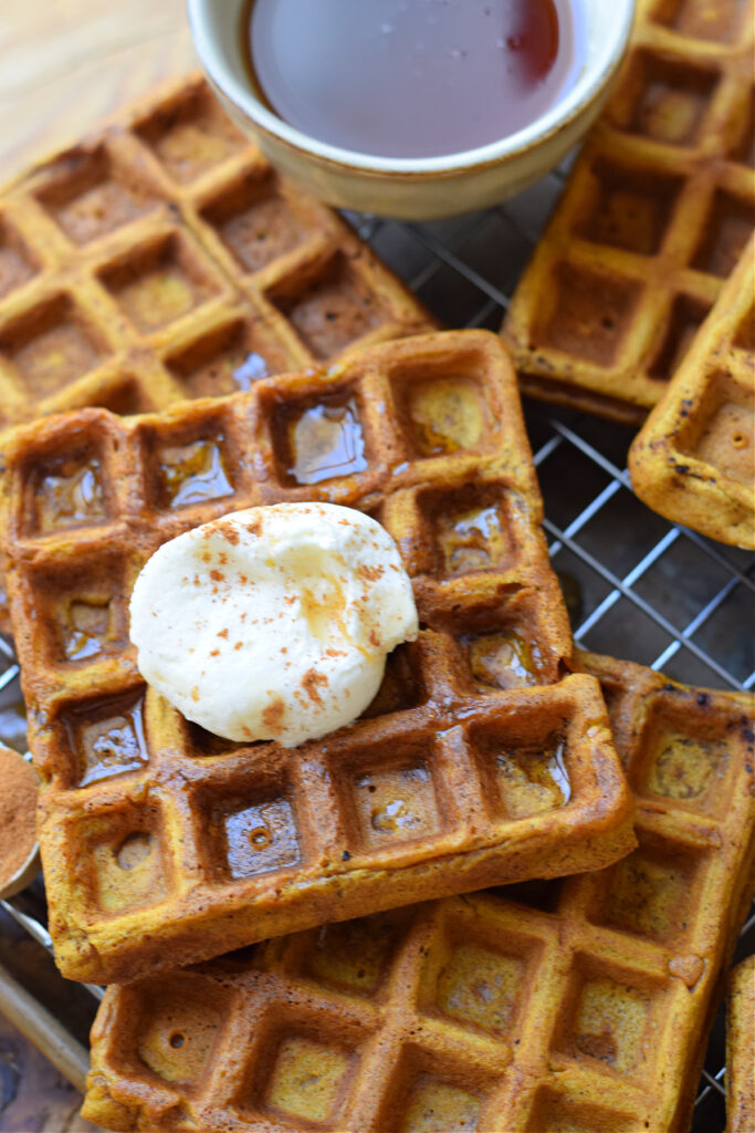 Close up of pumpkin waffles with whipped cream.