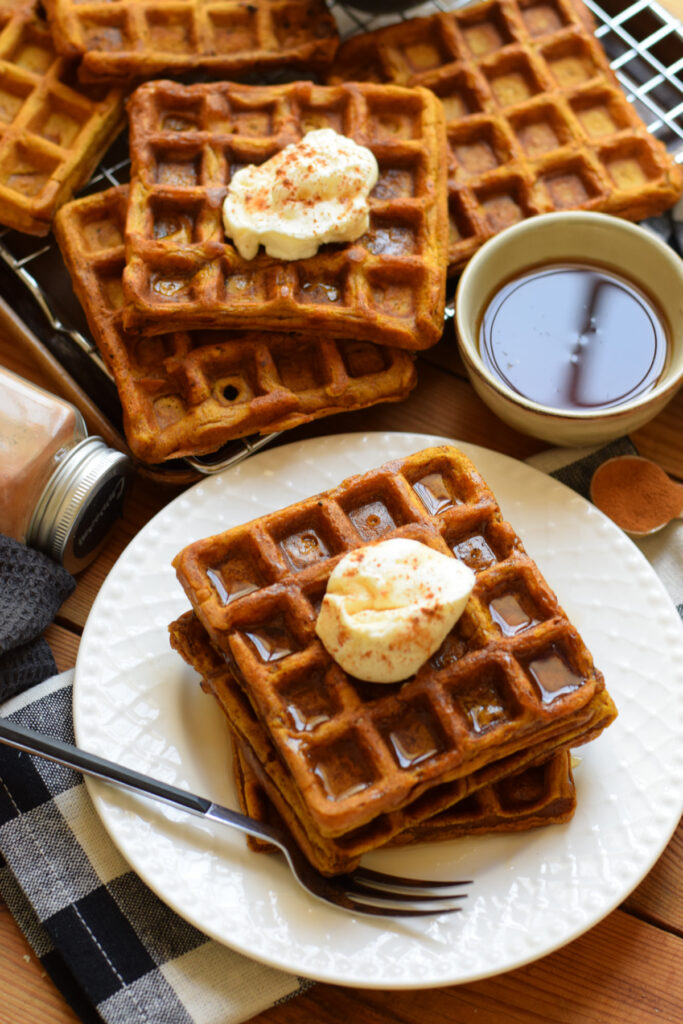 Buttermilk waffles on a plate with whipped cream.