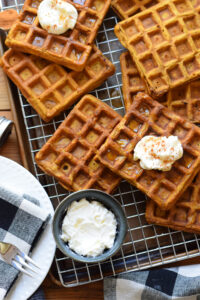Pumpkin waffles on a baking tray with whipped cream.