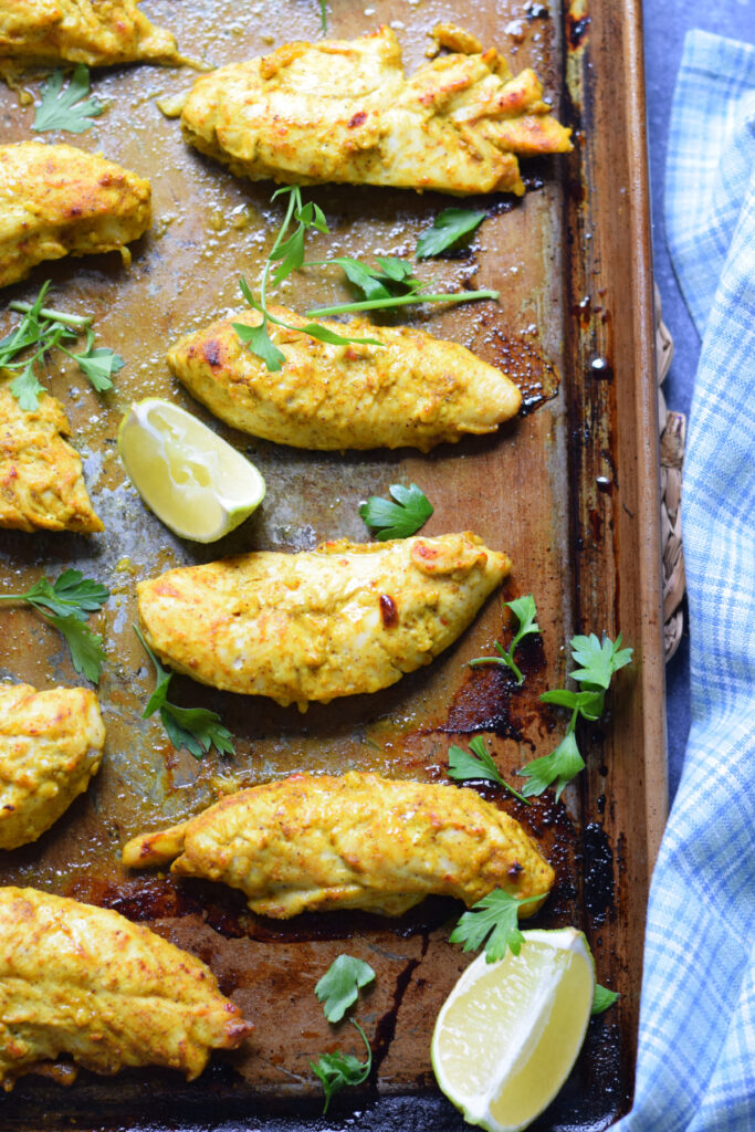 Indian spiced chicken tenders on a baking tray.