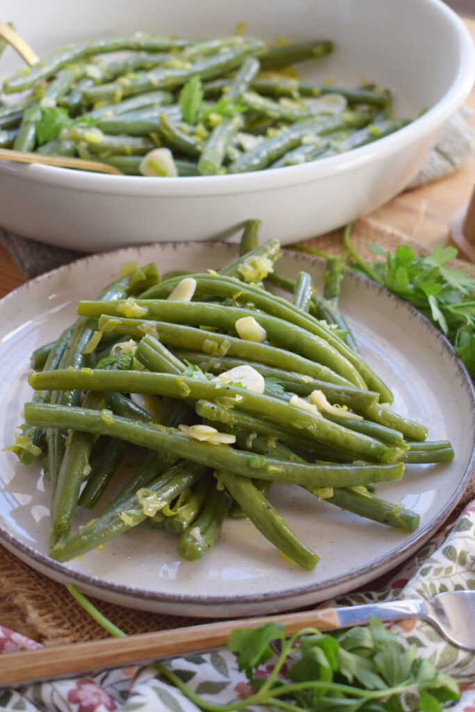 Close up of garlic sauteed green beans on a white plate.
