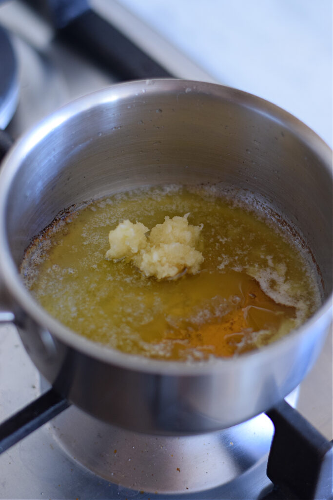 Adding garlic and honey to melted butter.