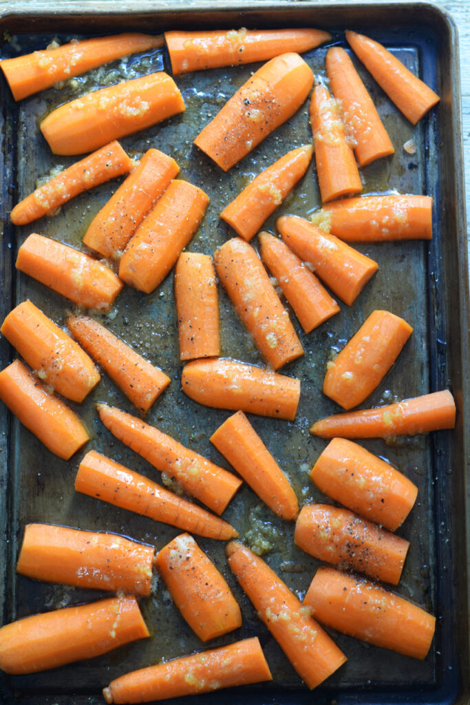 Ready to roast carrots on a baking tray.