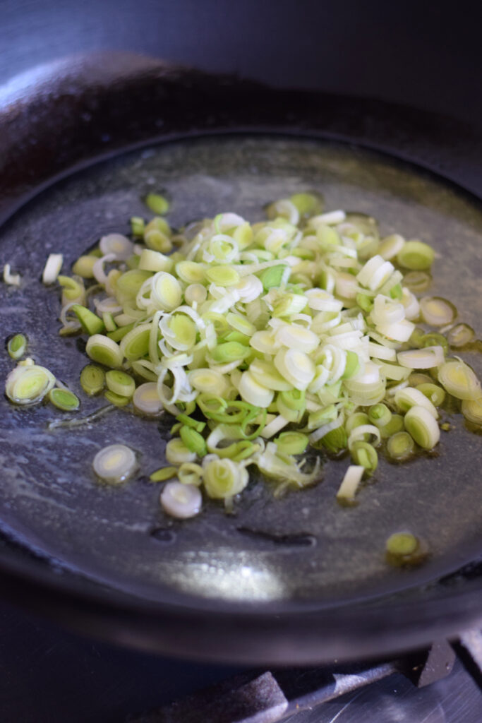 Cooking spring onions in a skillet.