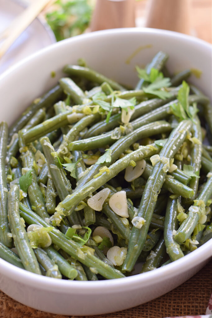 Sauteed green beans in a white serving dish.