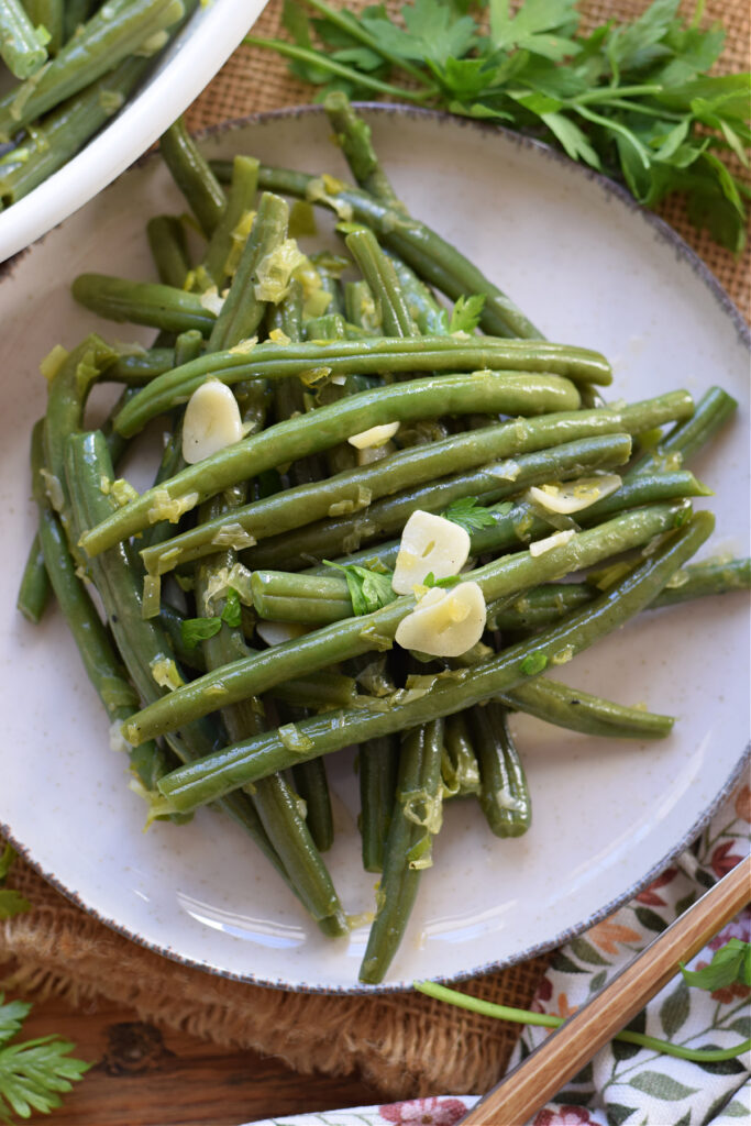 Garlic butter sauteed green beans on a white plate.