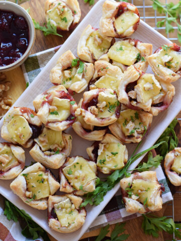Cranberry brie bites on a white serving dish.