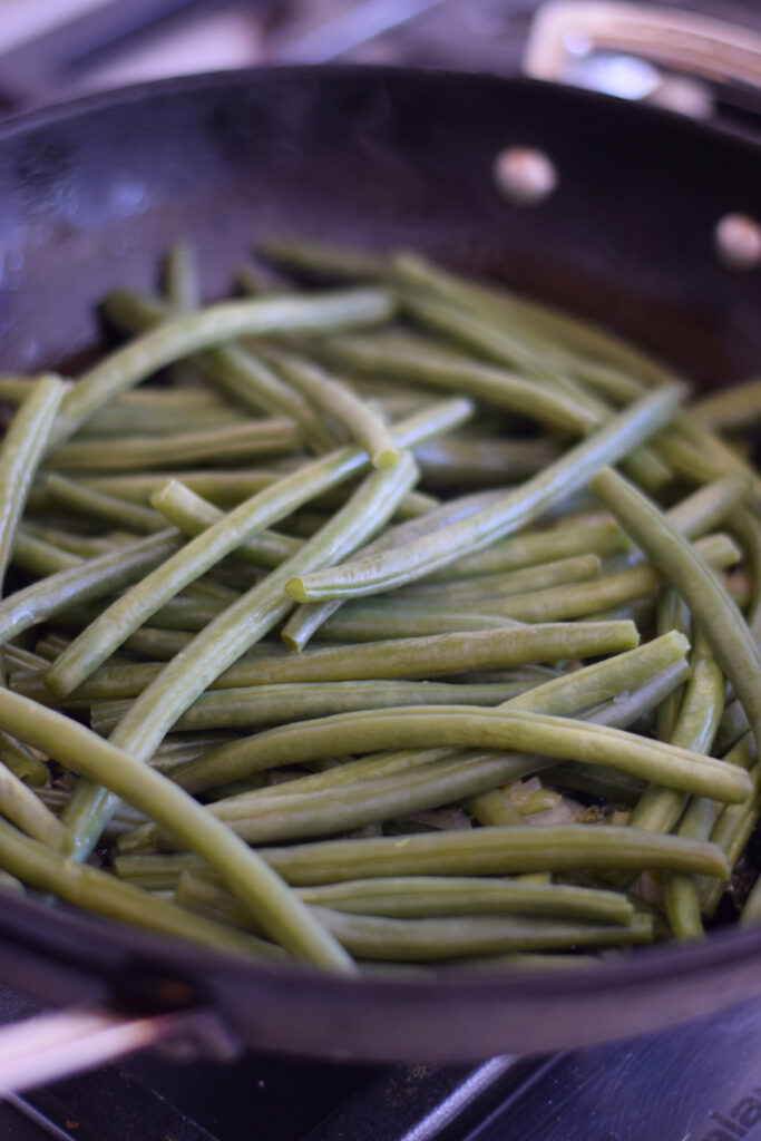 Cooking green beans in a skillet.