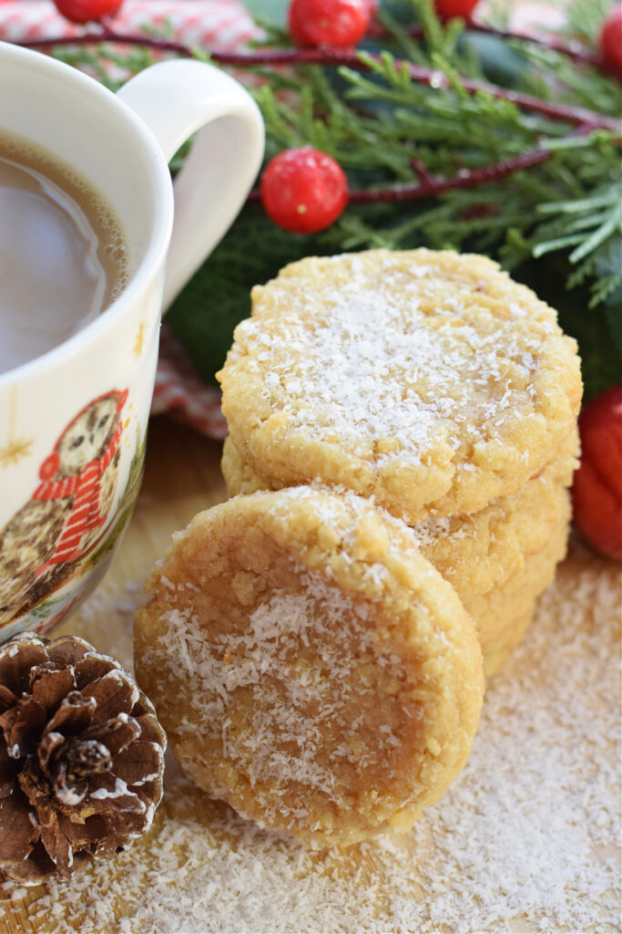 A stack of coconut cookies with a christmas mug.