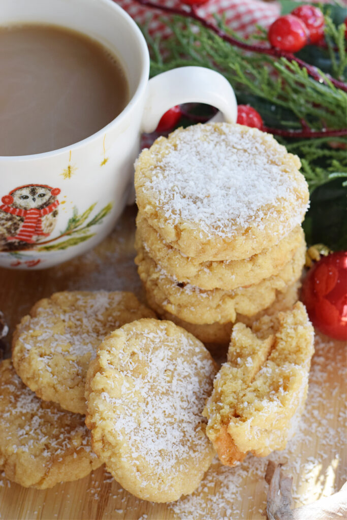 A stack of coconut cookies with a christmas mug.