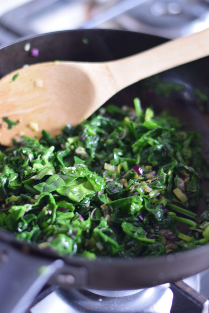 Cooking spinach in a skillet.
