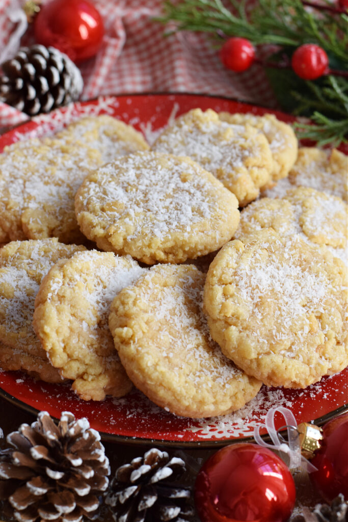 Chewy coconut cookies on a red christmas plate with pine cones.