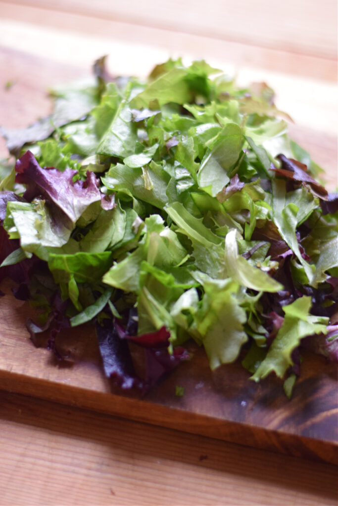 Chopped salad leaves on a wooden board.