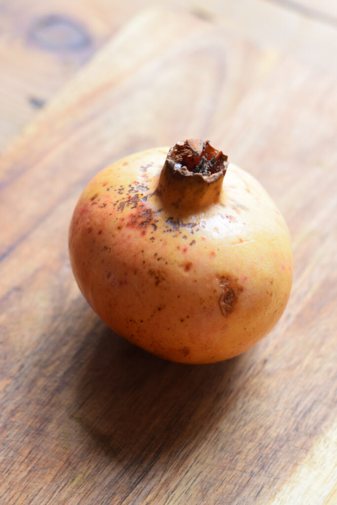 A pomegranate on a wooden board.