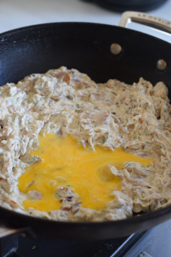 Adding a whisked egg to the mushroom filling.