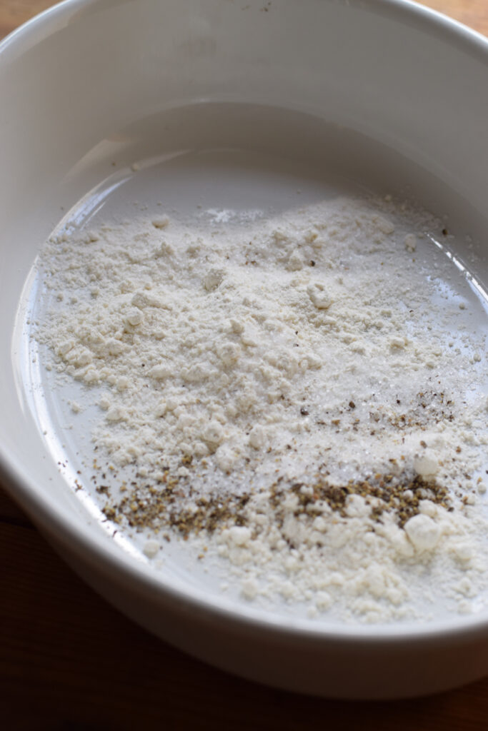 Flour with seasonings in a white bowl.