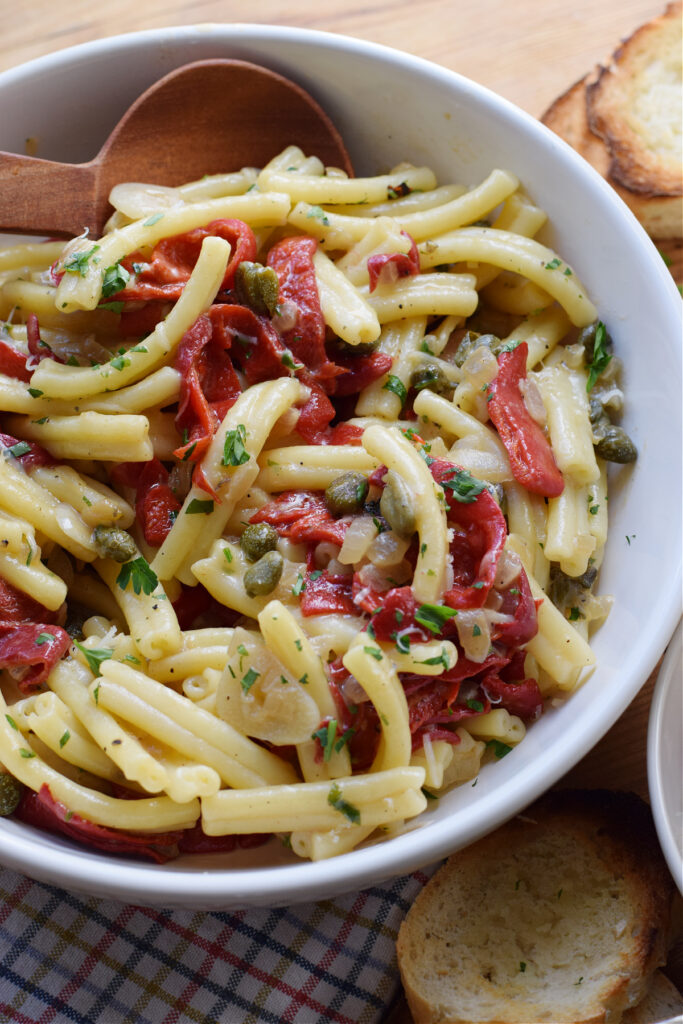 Pasta in a bowl with roasted red peppers and capers.
