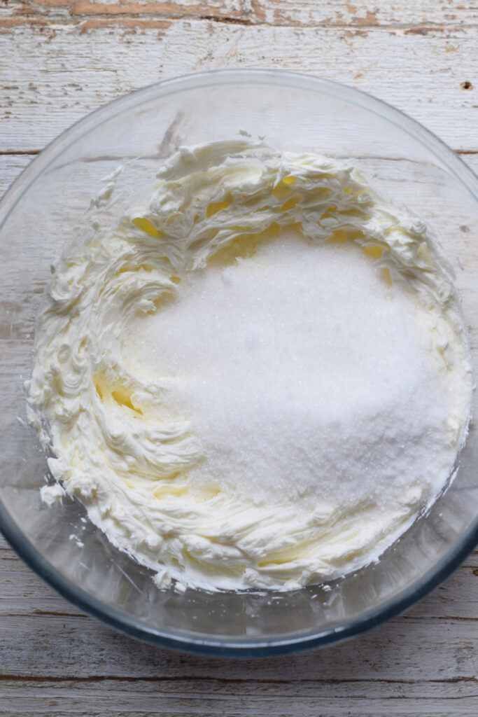 Adding sugar to whisked cream cheese.