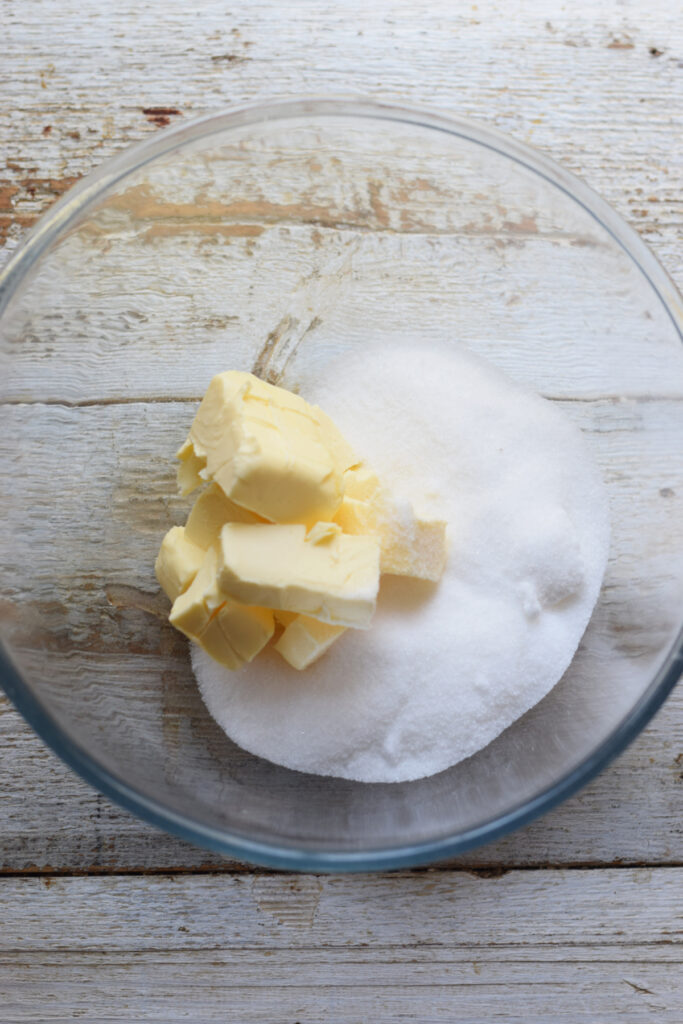 Butter and sugar in a glass mixing bowl.