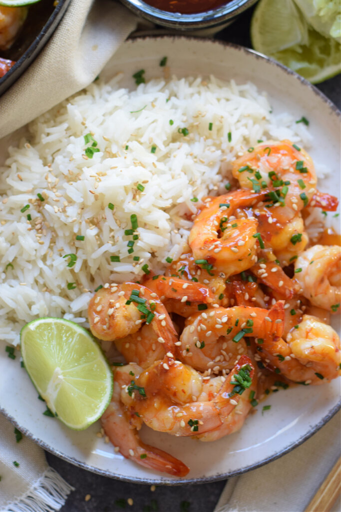 Shrimp and rice on a plate with a lime wedge.