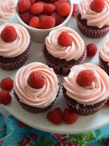 Pink frosted cupcakes on a white plate.