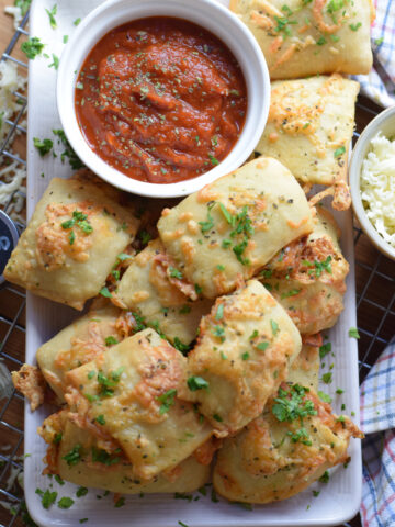 Pizza pocket bites on a plate with a dipping sauce.