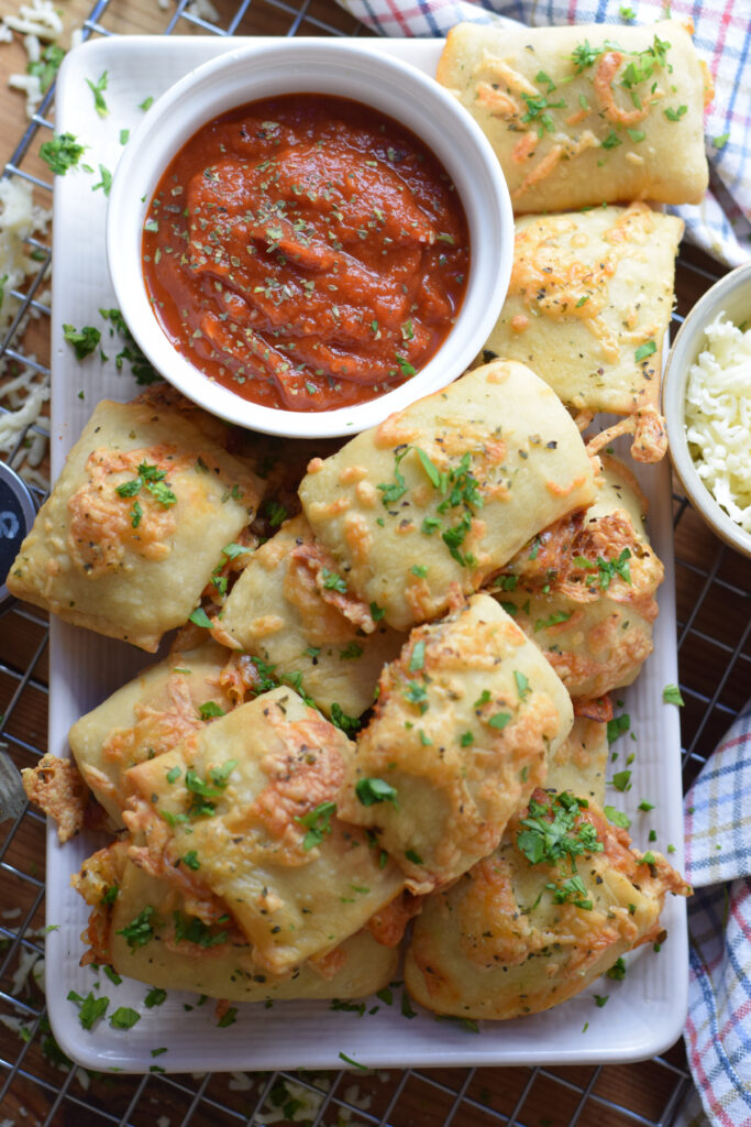 Pizza pocket bites on a plate with a dipping sauce.