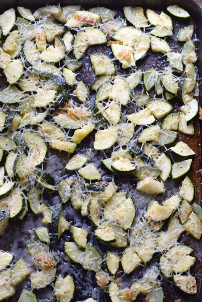 Roasted zucchini on a tray with parmesan cheese.