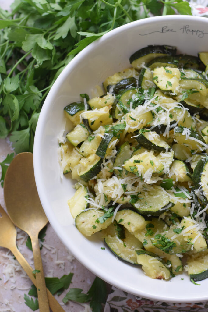 Zucchini in a bowl topped with parmesan cheese.
