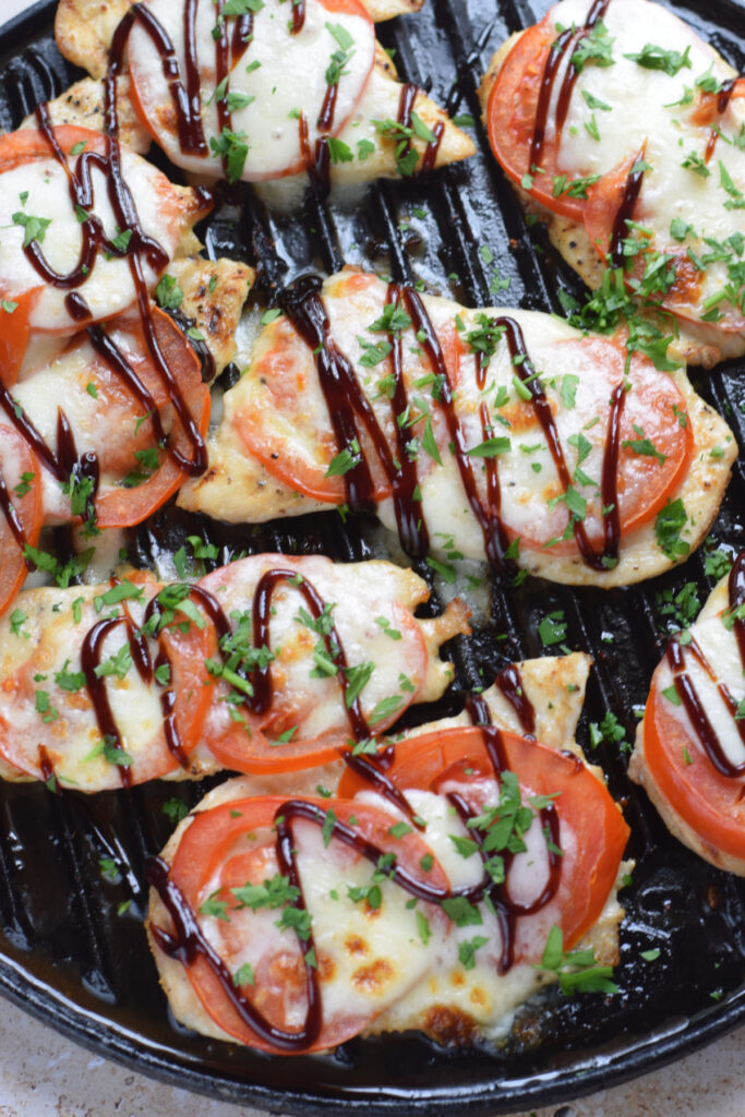 Tomato topped chicken in a skillet.