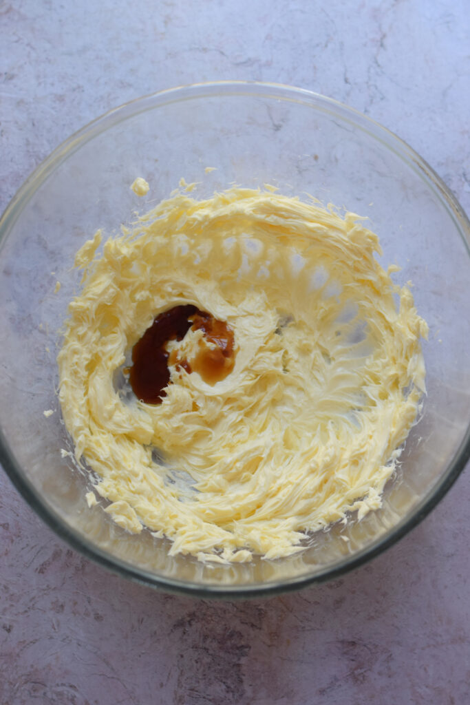 Adding vanilla extract to whipped butter.