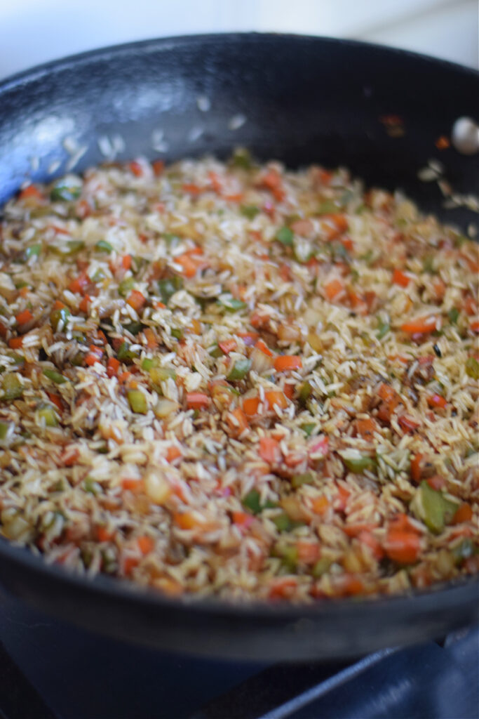 Cooking rice with peppers in a skillet.