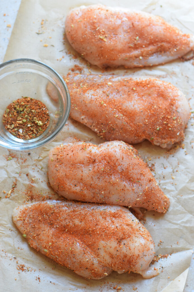 Chicken breast seasoned with Cajun seasoning on parchment paper.