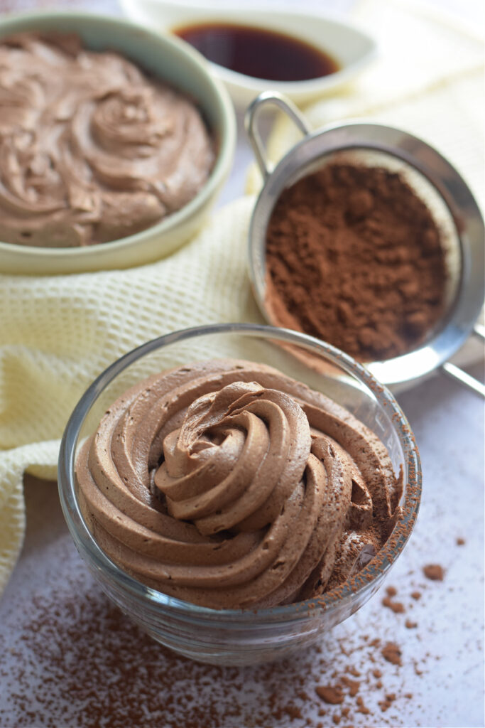 Close up of chocolate frosting in a glass bowl.