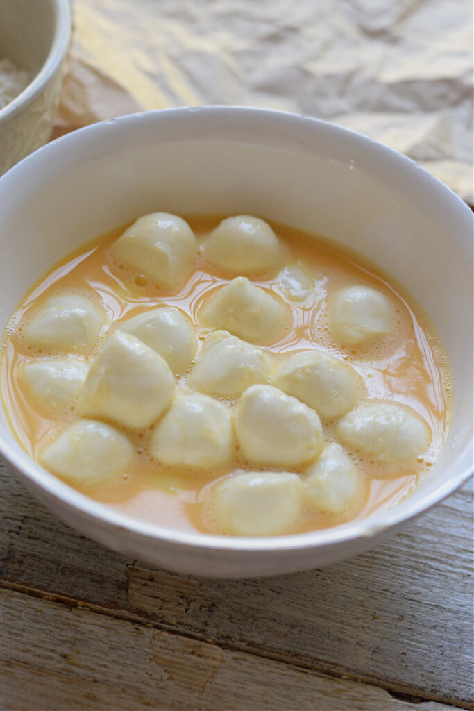 Mozzarella balls in whisked eggs.