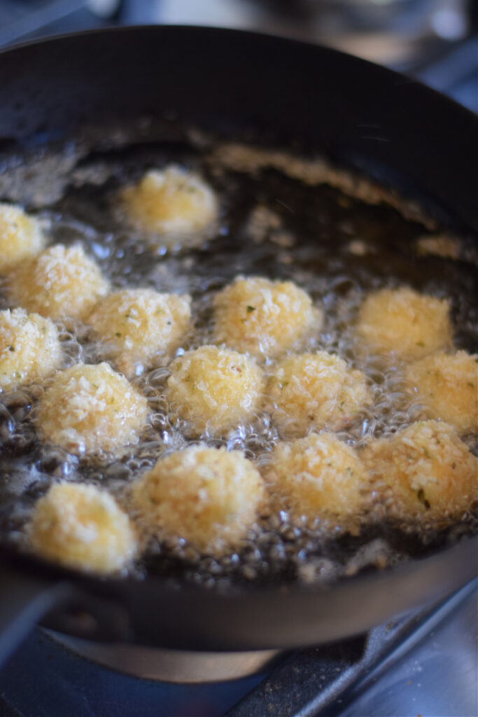Frying mozzarella balls in vegetable oil.