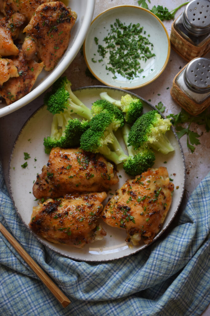 Baked chicken thighs on a plate with broccoli.