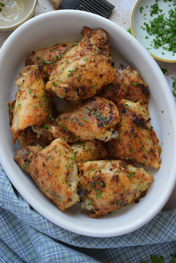 Oven baked chicken thighs in a white serving dish.