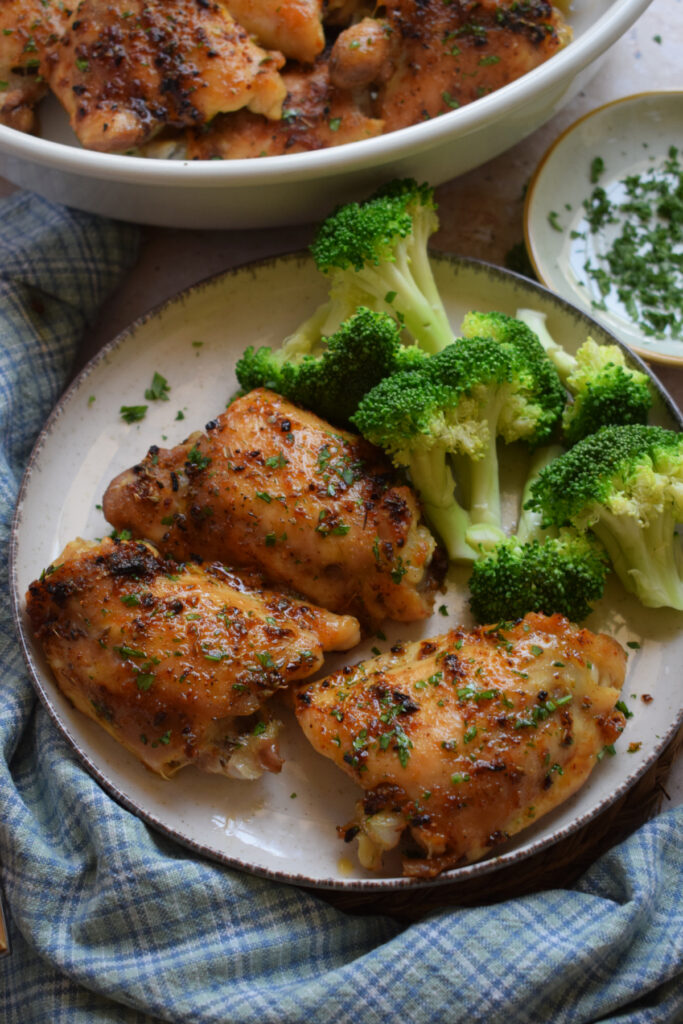 Oven baked chicken thighs with broccoli on a plate.