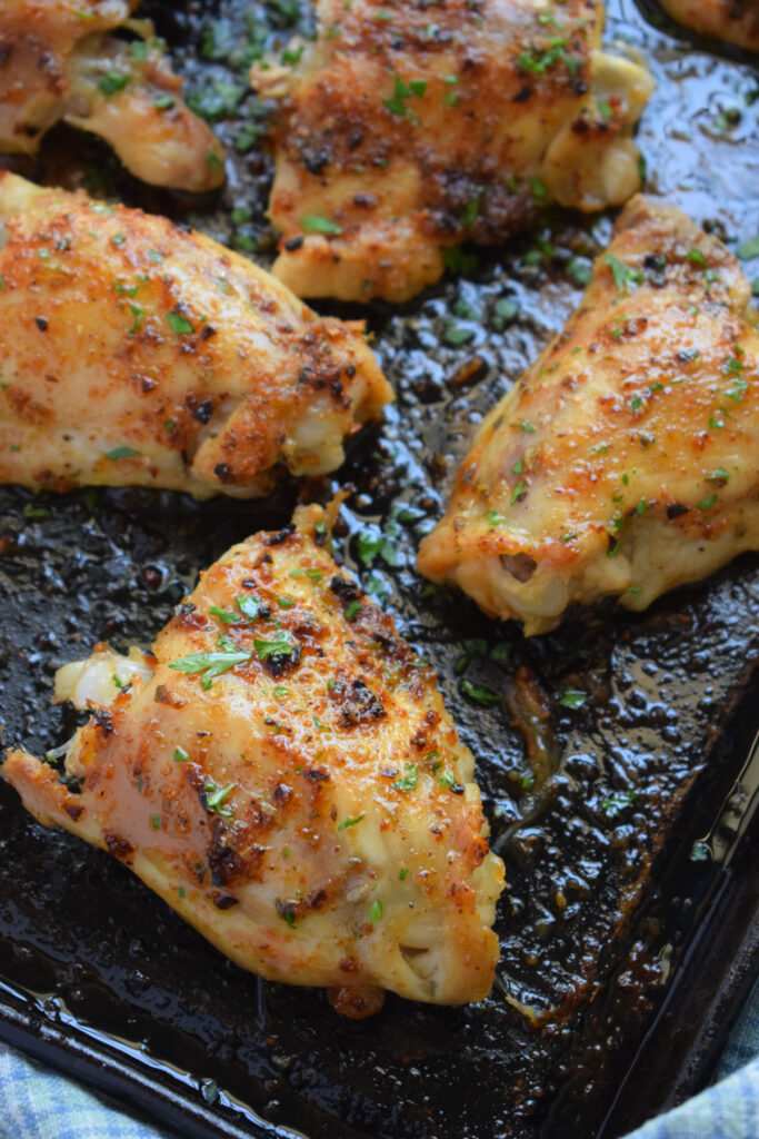 Close up of baked chicken thighs on a baking tray.