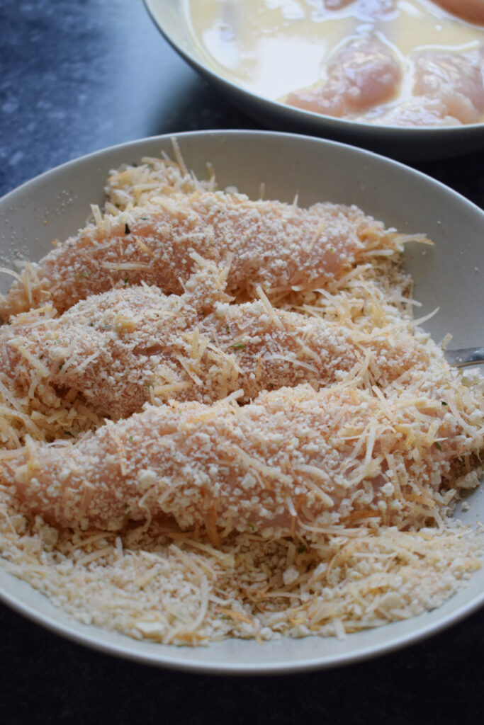 Coating chicken tenders in bread crumb mixture.