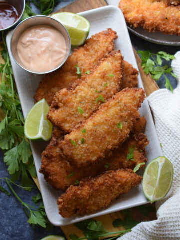 Fried chicken on a plate with a dipping sauce.