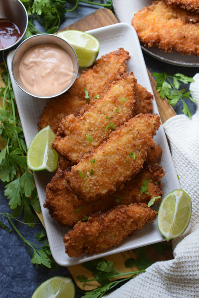 Fried chicken on a plate with a dipping sauce.