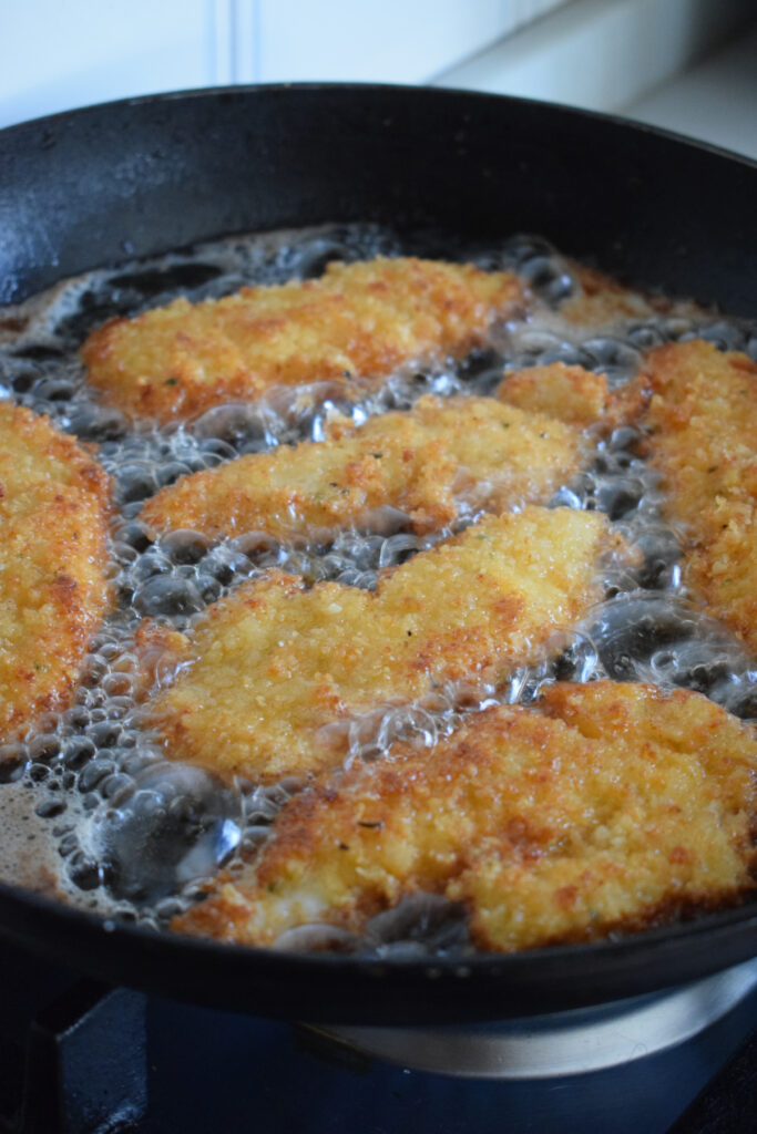 Cooking chicken tenders in hot oil in a skillet.