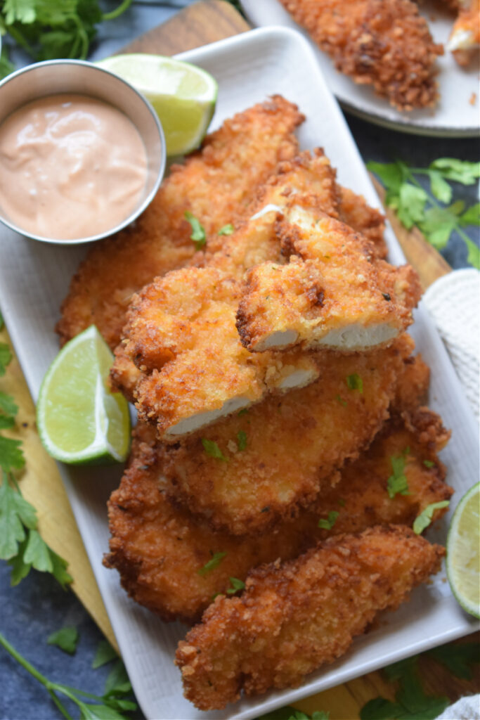 Panko crusted chicken tenders on a plate.