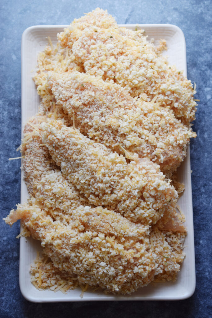 Chicken tenders ready to fry on a plate.